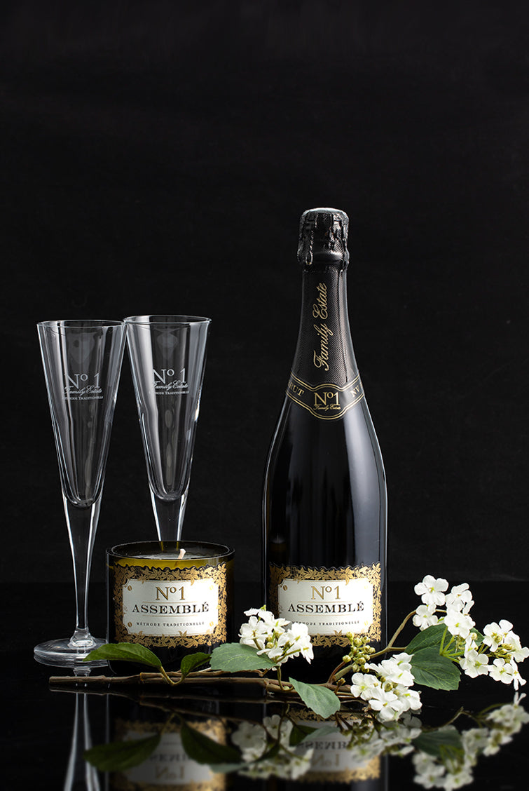 No.1 Family Estate gift pack with Assemble methode traditionelle, two flutes a candle and faux flowers on a black background